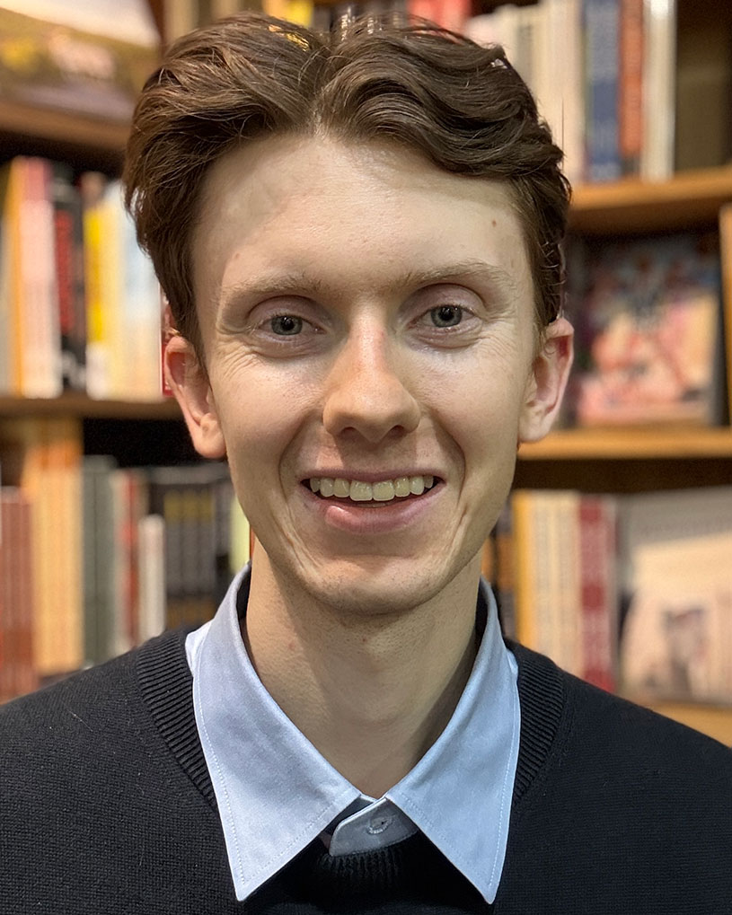 Head and shoulders portrait of Henry Shand, a young man with light skin and auburn hair. He is smiling for the camera.