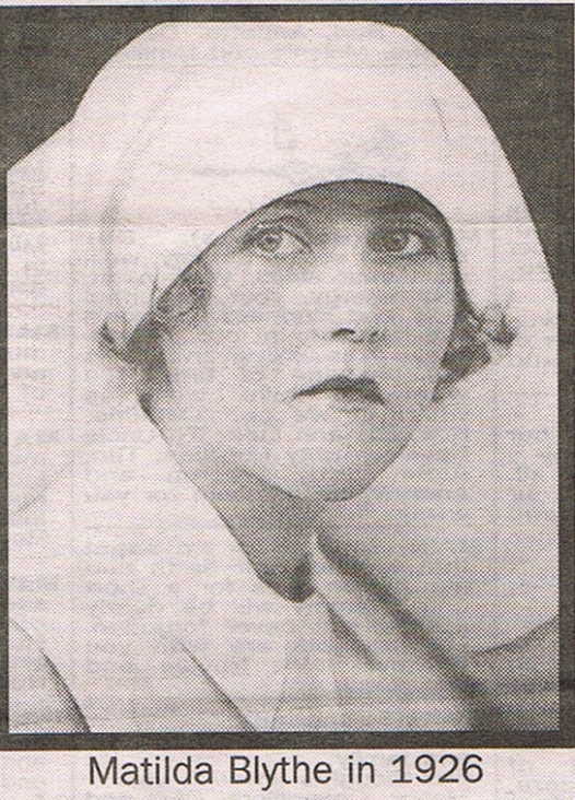 Black and white photogtraph of Matilda Blythe. She is pictured in a head-and-shoulders portrait, wearing a nurses uniform, including a cap which covers her hair. Though she faces the camera, her eyes look left at something out of frame. She is wearing dark lipstick. Text at the bottom of the picture states her name and the year, 1926.