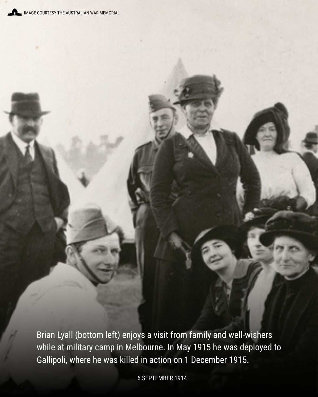 Group of men and women gathered outdoors at a military camp in Melbourne, 1914, with tents visible in the background. A young man in military uniform in the bottom of the photo is Brian Lyall, who the others were there to visit. He would die the following year in Gallipoli.